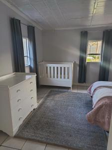 a bedroom with a bed and a dresser and a crib at Winemaker's Rest in Oudtshoorn
