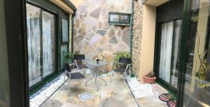 patio ze stołem i krzesłami oraz kamienną ścianą w obiekcie Pension Siete en el Camino w mieście Sarria