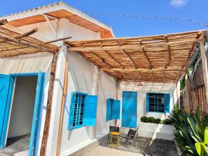 une maison blanche avec des fenêtres bleues et une pergola en bois dans l'établissement MIA Villa, à Tiến Thành