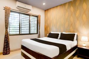 a bedroom with a large bed and a window at Townhouse Beltola Tiniali Formerly Hotel Pratishtha in Guwahati