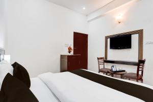 a bedroom with a bed and a chair and a television at Palette by CheckIn Sarnath Temple in Varanasi