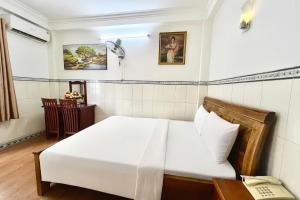 a bedroom with a white bed and a telephone at TK Diamond Hotel - Saigon Center in Ho Chi Minh City