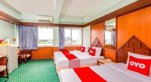 ein Hotelzimmer mit 2 Betten in Rot und Weiß in der Unterkunft OYO 441 Grand Thara Hotel in Surat Thani