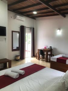 a bedroom with two beds and a desk with a table at Kandy Home Stay in Kandy