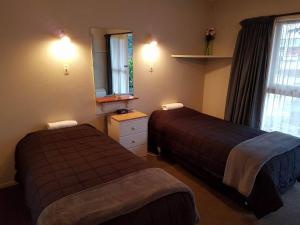 ヘイスティングズにあるCamberley Court Motelのベッドが2つと鏡があるホテルの部屋 +19枚の写真