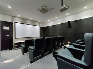 a cinema room with chairs and a projection screen at Bhartiya City 2 BHK Nikoo Living in Bengaluru +41 photos
