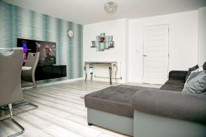 a living room with a couch and a flat screen tv at Unbeatable Value I Best Rates I Garden I Wi-Fi I Parking in Stanford le Hope