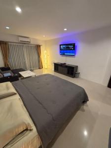 a bedroom with a large bed and a flat screen tv at Lamai Beachroad Apartment in Lamai
