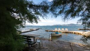 a table and chairs and a boat in the water at Villa Sunj in Drače