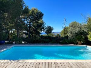 a swimming pool in a yard with a wooden deck at LA CIVADE in La Ciotat