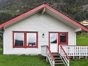 a white house with red windows and a porch at 7 person holiday home in Selje in Selje