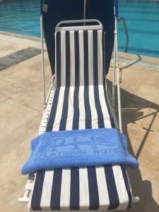 Ein blau-weiß gestreifter Stuhl steht neben einem Pool. in der Unterkunft Platinum Hotel in Tyros