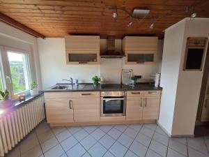 a kitchen with wooden cabinets and a sink at Gemütliches Apartment in Albbruck +10 photos