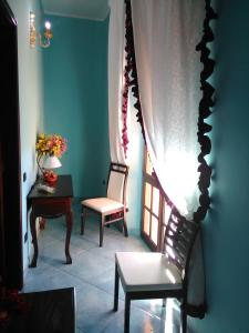 Zimmer mit einem Stuhl, einem Tisch und einem Fenster in der Unterkunft Villa Donna Maria in Capoterra