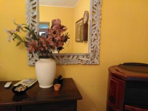 eine Vase aus Blumen auf einem Tisch mit einem Spiegel in der Unterkunft Villa Donna Maria in Capoterra