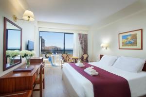 a hotel room with a bed and a desk and a window at Odysseia Hotel Kapetanios in Limassol