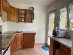 a kitchen with wooden cabinets and a microwave at Villa "La Tourelle" avec piscine privée in Haguenau