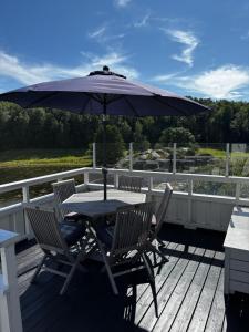a table and chairs with an umbrella on a deck at Pollyville in Lillesand