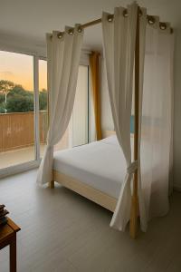 a bedroom with a bed with curtains and a window at Au Calme VUE MER in Saint-Brévin-lʼOcéan