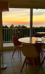 a dining room with a table and chairs and a balcony at Au Calme VUE MER in Saint-Brévin-lʼOcéan