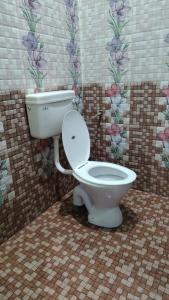 a bathroom with a toilet in a tiled room at JK Homes in Kolli Hills