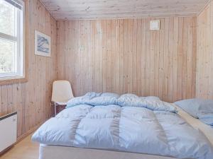 a bed in a room with a wooden wall at 4 person holiday home in Nexø in Neksø
