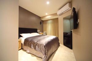 a hotel room with a bed and a flat screen tv at E-House Xining Branch in Taipei