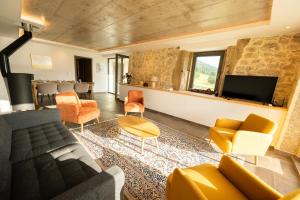 a living room with a couch and chairs and a tv at Le 214, Entre Lacs et Montagnes in Les Rousses