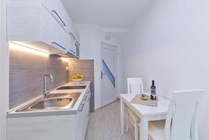 a white kitchen with a sink and a table at Villa Porto in Mlini +28 photos