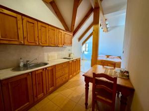 a kitchen with wooden cabinets and a sink and a table at Hotelový a jezdecký areál Dvůr Krutěnice in Krutěnice