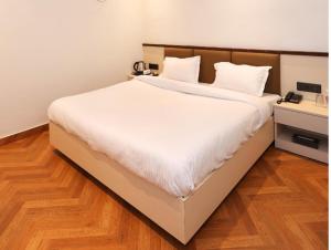 a large white bed in a room with a wooden floor at Shree Jayati Inn in Ayodhya