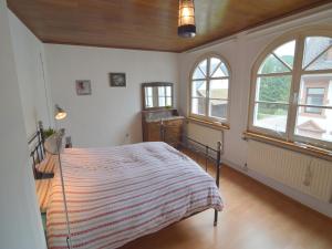a bedroom with a bed in a room with windows at Veltenhaus Historic Retreat in Mürlenbach