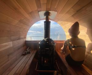 a woman sitting in a sauna looking out a window at TORIKKA Stay -海だけが見える宿- in Sumoto