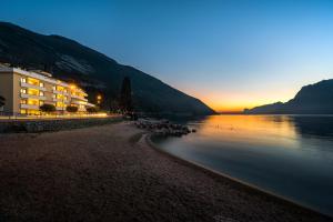 a view of a beach with a building and the water at Torbole Aparthotel in Nago-Torbole