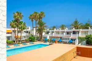 a view of the pool at a resort with palm trees at Panarea Chaparal in Costa Del Silencio