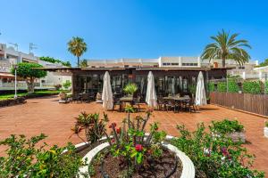 a patio with tables and white umbrellas at Panarea Chaparal in Costa Del Silencio