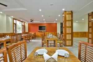 ein Esszimmer mit Holztischen und Stühlen in der Unterkunft Marina Group of hotels Pine View Sudher- Best Prices Guaranteed with Deals- Free Parking-cricket stadium 5 km-Mountain View in Dharamshala