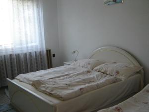 an unmade bed in a bedroom with a window at Somogyi Vendégház in Zamárdi