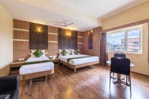 a hotel room with two beds and a window at Treebo Trend ESS Grande in Coimbatore