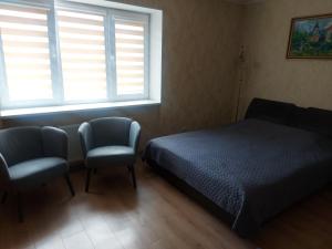 a bedroom with a bed and two chairs and a window at Dzīvoklis in Ventspils