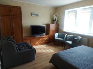 a bedroom with a tv and a bed and chairs at Dzīvoklis in Ventspils
