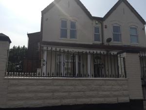 a white house with a black fence at Vicarage Lodge Birmingham in Birmingham