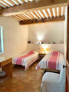 two beds in a room with wooden ceilings at Maison paisible au coeur du Luberon in Bonnieux