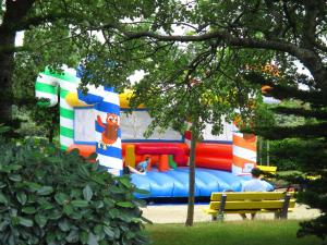 a man sitting on a bench in front of a inflatable playground at VVF Les Plages de Guérande La Turballe in La Turballe