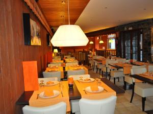 a restaurant with tables and white chairs and a light fixture at Hotel Solineu in La Molina