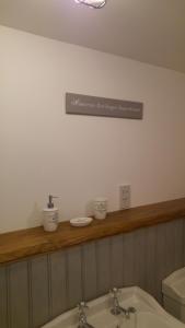 a bathroom with a sink and a sign on the wall at The Barn at Cae Bach in Gwalchmai