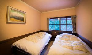 two beds in a room with a window at Pension Kinoshita in Takayama