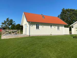 a white building with an orange roof on a yard at Hansingastugan Bed and Kitchen Guesthouse in Varberg