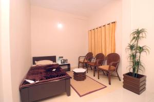 a bedroom with a bed and chairs and a table at HIGHLAND Hills in Coonoor