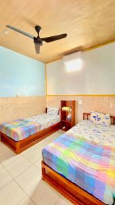 a bedroom with two beds and a ceiling fan at Sawitri Homestay in Padangbai